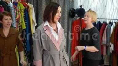 时尚的女人在配饰店尝试项链。 卖家帮助尝试优雅的项链在时尚的配件